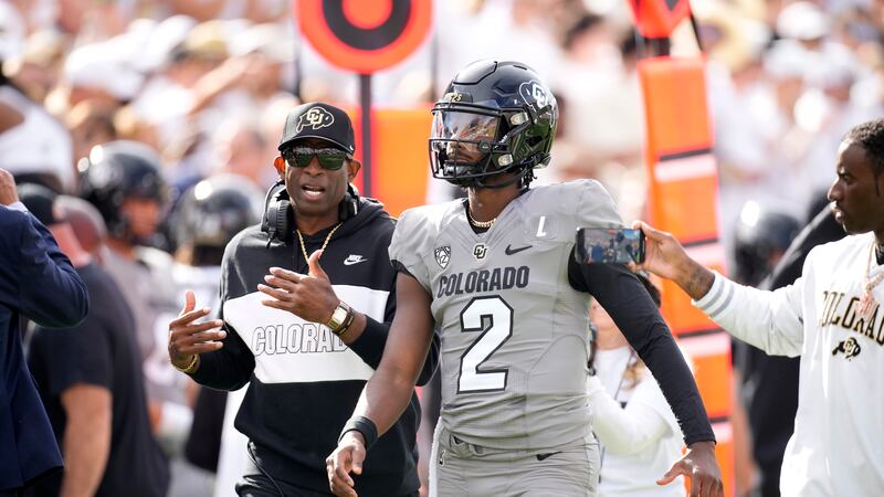 Colorado head coach Deion Sanders, left, talks with his son, quarterback Shedeur Sanders,...