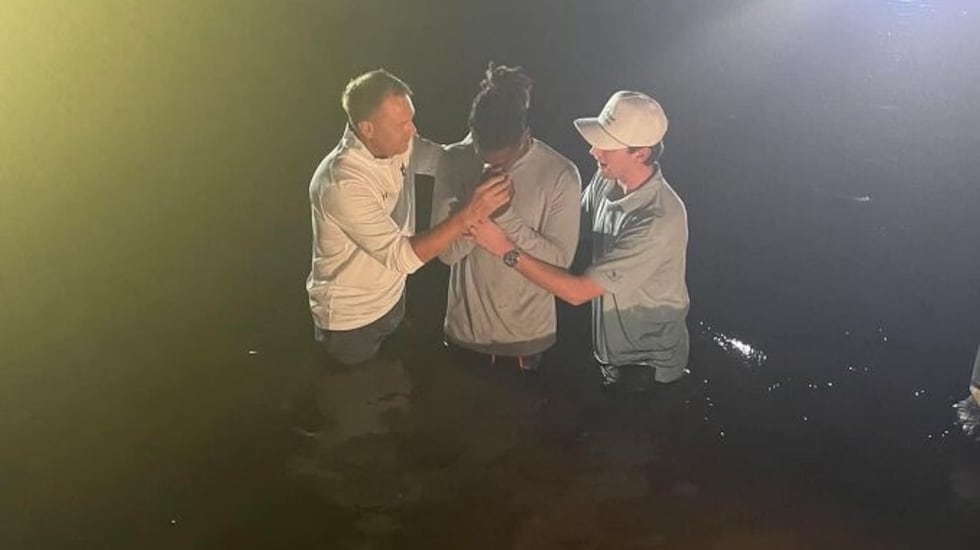 Auburn Tigers head football coach Hugh Freeze helps baptize one of the football players on his...