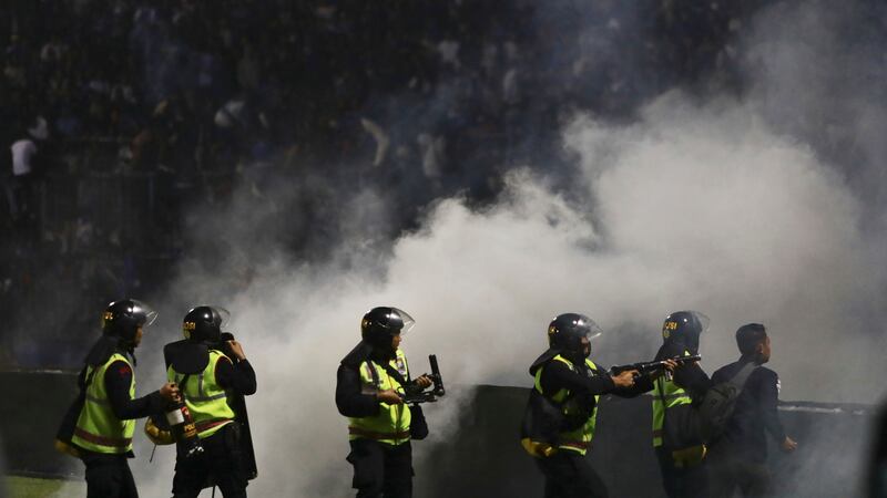 Police officers fire tear gas during a soccer match at Kanjuruhan Stadium in Malang, East...